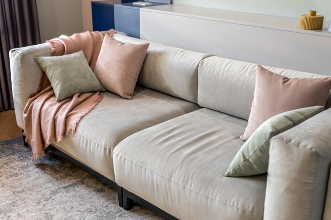 Il luogo centrale nel soggiorno ha un grande divano morbido con cuscini di volume tappezzeria grigio chiaro. Lui non capisce, ma le dimensioni si può utilizzare come un letto per una persona.