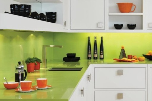 Il piano di lavoro e il grembiule di una tonalità di lime brillante sono perfetti in combinazione con i frontali della cucina bianca e i piatti arancioni.