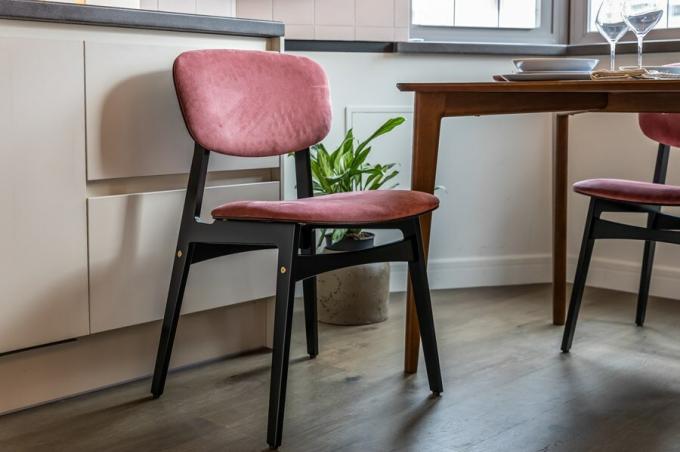 Ospitare il tavolo da pranzo invitano quattro sedie in multistrato di betulla rivestito con uno smalto resistente all'umidità, con schienali e sedili rivestiti in ricche tonalità rosa.