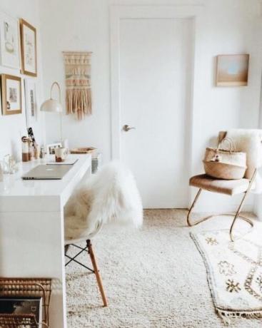 Home office in tonalità chiare, tavolo bianco lucido, macramè, tappetino, oggetti in vimini